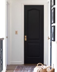 a black front door with a basket on the floor in front of it and an entry way