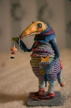 an animal figurine holding a bell on top of it's head and wearing a scarf