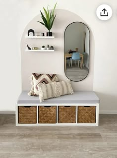 a white bench with baskets under it and a mirror above it on the wall behind it