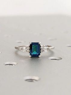 a blue and white ring sitting on top of a silver surface with drops of water around it