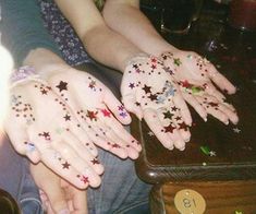 two hands with stars painted on them are sitting next to each other at a table