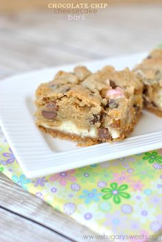 two pieces of chocolate chip cheesecake bars on a white plate next to a colorful napkin