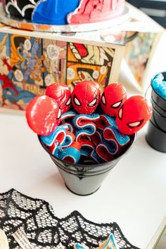 there are many spiderman candies in the bowl on the table next to each other