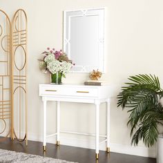 a white table with flowers and a mirror on it next to a potted plant