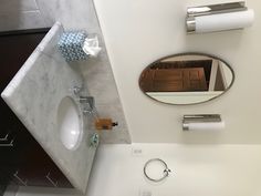 a bathroom with a sink, mirror and toilet paper dispenser on the wall