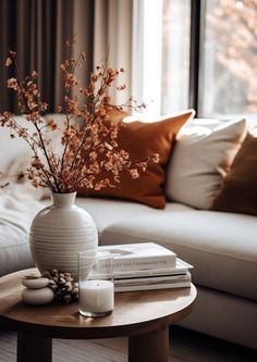 a living room with a couch, coffee table and vase filled with flowers on top of it