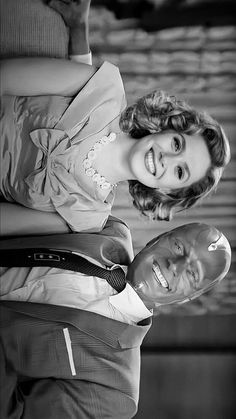 black and white photograph of a woman holding a hair dryer in her hand while smiling