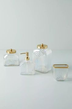 three clear glass containers with gold lids