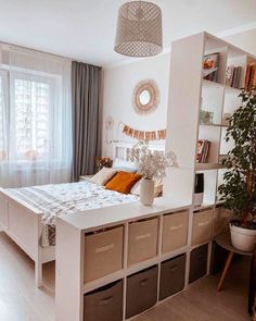 a white bed sitting next to a window with lots of storage boxes on top of it