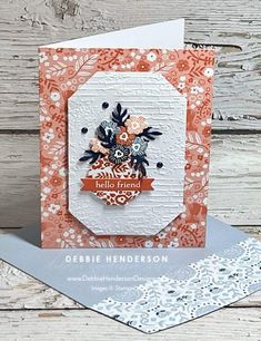 a close up of a card on a wooden surface with a white background and orange flowers