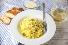 a white plate topped with pasta next to bread