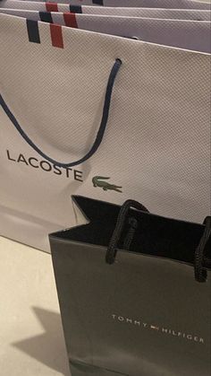 there are many bags on the table and one has a tag that says lacoste