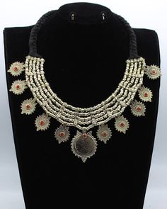 * This vintage coin necklace is an epitome of tradition, as the design of the set is inspired by the Afghani Kuchi ornaments. The rusty silver toned set is embellished with dangling elements, adorned with multicolor glass stones and archaic motifs. You can pair this necklace with any traditional or trendy outfit and make a unique fashion statement. Note: The product is handmade, slight change might occur in the actual product. Vintage Coin Necklaces For Festival, Handmade Bohemian Coin Medallion Necklace, Handmade Coin Medallion Necklace In Bohemian Style, Vintage Metal Coin Necklace, Handmade, Antique Handmade Coin Necklace For Festival, Handmade Metal Coin Necklace For Festival, Handmade Antique Coin Necklace For Festival, Vintage Handmade Metal Coin Necklace, Bohemian Coin Pendant Necklace For Rituals