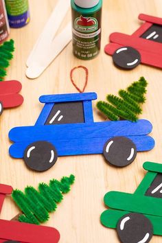 a wooden table topped with popsicle cars and pine tree cutouts on top of it