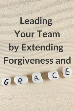 the words leading your team by extending forgingness and grace written on rocks in sand