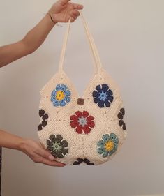 a woman holding a crocheted purse with flowers on it's front and sides