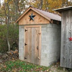 an outhouse in the woods with stars painted on it's roof and door