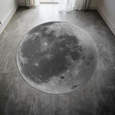 a large round rug in the middle of a room with a window and curtain behind it