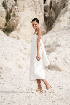 a woman in a white dress walking on the beach