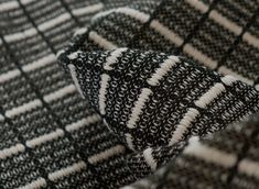 an up close shot of a black and white patterned material with lines on the fabric