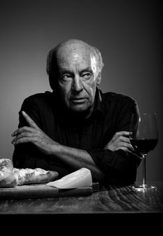 a man sitting at a table with a glass of wine and some bread on it