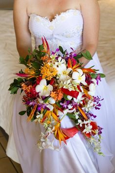 a woman in a white dress holding a bouquet of flowers on her wedding day,