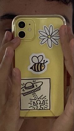 a person holding up a cell phone case with stickers on the back of it