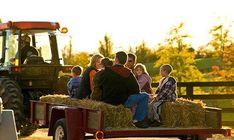 a group of people sitting on the back of a red truck in front of a tractor