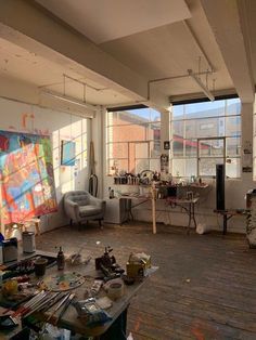 an artist's studio with large windows and lots of art supplies on the floor