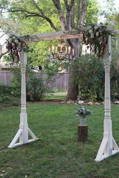 an outdoor wedding ceremony setup with flowers and greenery on the arbor, in front of a tree