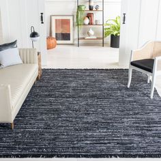 a living room with white walls and black rugs on the floor next to a couch