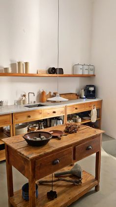 a wooden table with bowls and pans on it in front of a kitchen counter