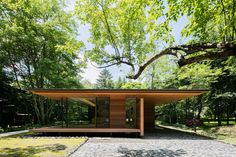 a wooden structure in the middle of a park with lots of trees and grass around it