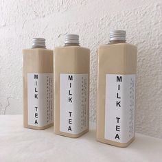 three bottles with labels on them sitting next to each other in front of a white wall