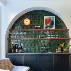 an arch in the wall is filled with wine bottles and glasses on top of black cabinets