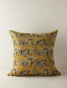 a yellow pillow with black and white zebras on the front, sitting against a wall