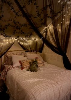 a teddy bear sitting on top of a bed under a canopy covered in fairy lights