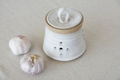 two garlic cloves sitting next to a white container with a lid on it