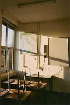 an empty classroom with desks and chairs in front of a large map on the wall