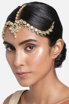 a woman wearing a gold and green headpiece with jewels on it's forehead