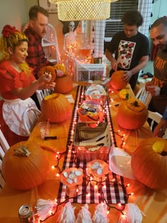 a group of people standing around a table with pumpkins