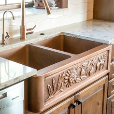 a kitchen sink with an intricate design on the front and side, surrounded by marble counter tops