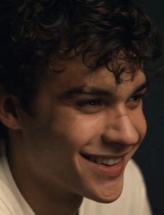 a close up of a person wearing a shirt and tie with curly hair smiling at the camera