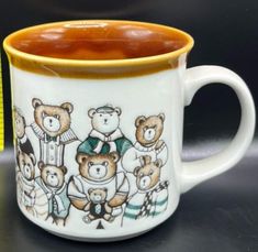 a coffee mug with bears on it sitting on a table next to a measuring tape