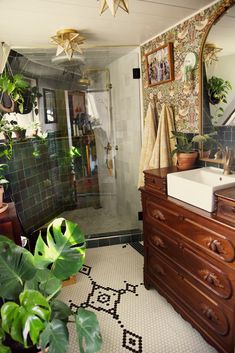 a bathroom with a sink, mirror and plants in the shower stall next to it