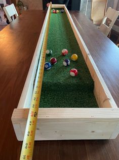 a wooden table topped with lots of balls and a tape measure in front of it