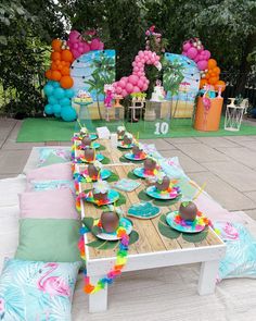 a table set up for an outdoor party with balloons and plates on the table,