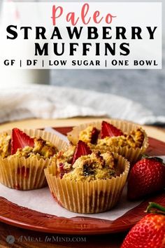 three strawberry muffins on a plate with strawberries next to it and text overlay that reads paleo strawberry muffins gf diy low sugar one bowl