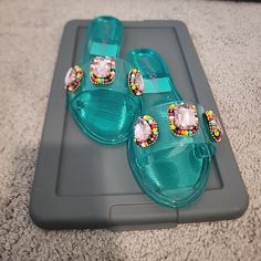 Add A Pop Of Glam To Your Shoe Collection With These Betsey Johnson Women's Madilyn Jelly Sandals. The Black Jelly Sandals Are Adorned With Glitter, Beaded, And Rhinestone Accents, Making Them Perfect For A Night Out Or Any Occasion That Calls For Some Sparkle. These Flat Sandals Feature A Pvc Upper Material And A Slide Style For Easy Wear. The Madilyn Model Comes In Size 6 And Is Brand New In Box. Whether You're Pairing Them With A Casual Outfit Or Dressing Up, These Sandals Are Sure To Add Som Blue Slip-on Jelly Sandals For Summer, Blue Jelly Sandals With Round Toe For Party, Turquoise Open Toe Sandals For Party, Turquoise Open Toe Sandals For Summer, Turquoise Synthetic Sandals For Spring, Trendy Blue Open Toe Jelly Sandals, Blue Flat Jelly Sandals For Summer, Blue Jelly Sandals For Spring Party, Blue Open Toe Jelly Sandals For Summer