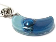 Baby blue and Blue moon shape glass pendant The Glass bead is approx 1.25'' long and .75'' wide. The chain is approx 18 inches long. Silver Plated "snake" chain with a lobster claw clasp. (if you need a longer chain please send a note with your purchase) All the jewelry is handmade out of recycled glass. This is real glass that comes from windows and other more traditional sources. The glass is cut and assembled, then fired in a kiln to fuse round sharp edges and improve the colors and texture o Blue Moon Phase Round Pendant Necklace, Blue Resin Round Pendant Necklace, Blue Teardrop Resin Jewelry, Blue Moon Charm Pendant Necklace, Blue Crescent Necklace For Gifts, Blue Crescent Necklace For Gift, Blue Moon Charm Necklace For Jewelry Making, Handmade Blue Moon-shaped Necklaces, Handmade Blue Moon Shaped Necklace